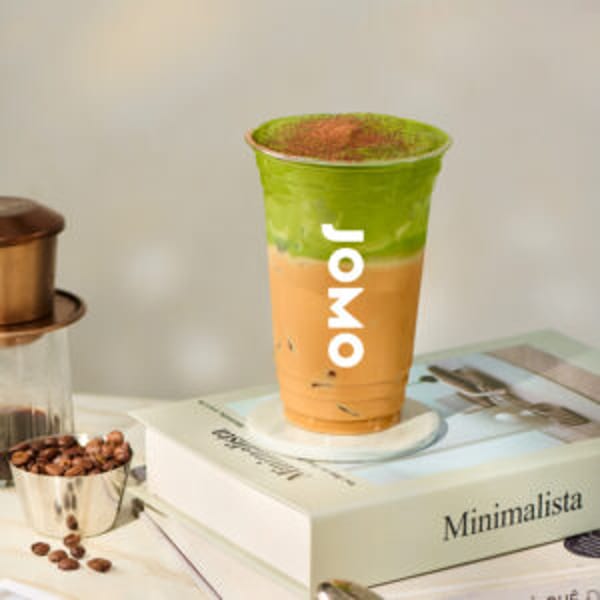 JOMO's layered matcha and coffee drink with coffee beans and a Vietnamese phin filter.